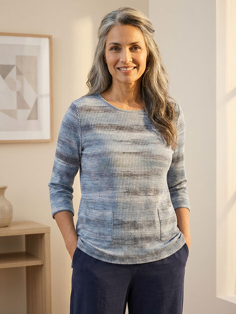 Blue textured print sweater. Woman smiling with hands in pockets