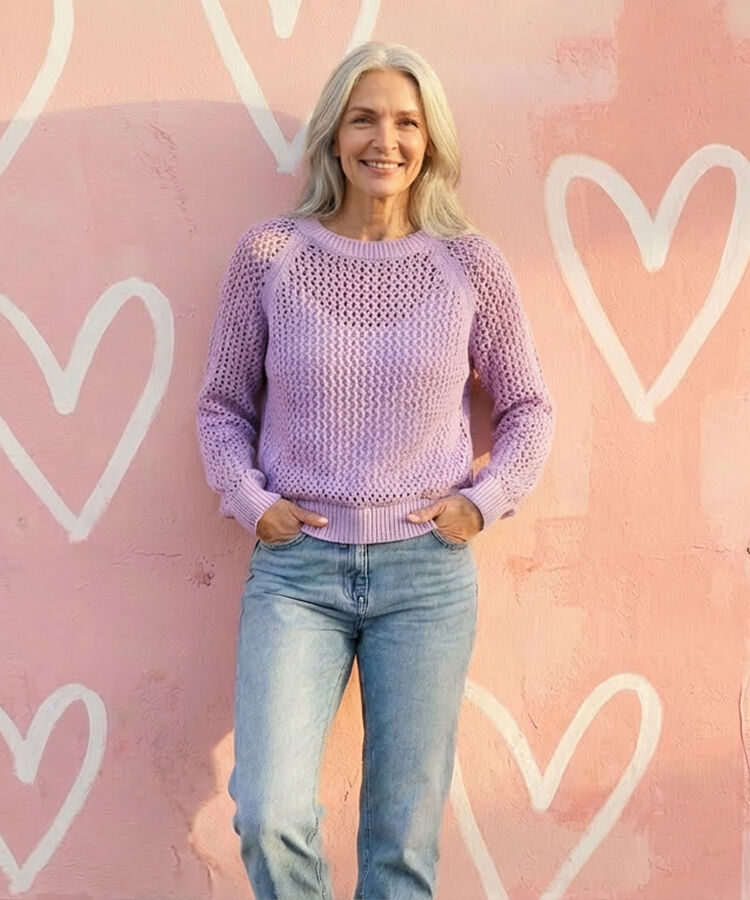 Smiling with laughter woman wearing fuchsia jean jacket and matching pant. Heart textured wall paper.
