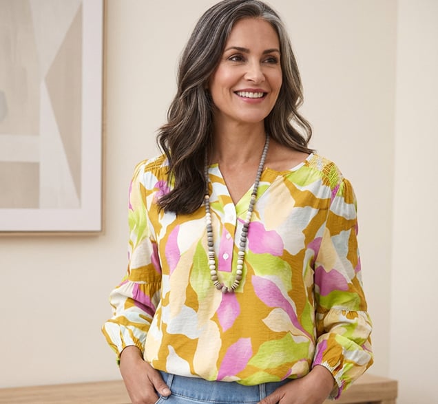 Woman smiling wearing a green pink orange floral printed blouse by tribal